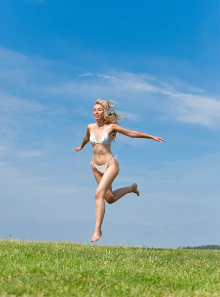 행복 한 젊은 여자가 들판에서 뛰어 내린다 — 스톡 사진