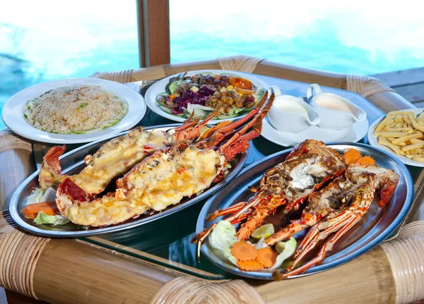 Dos platos con langosta en la mesa en la ventana con vista al océano — Foto de Stock