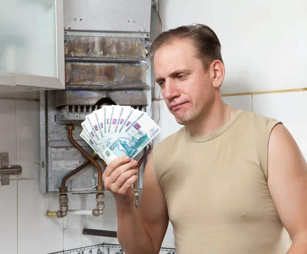 The sad man counts money for repair of a gas water heater — Stock Photo, Image