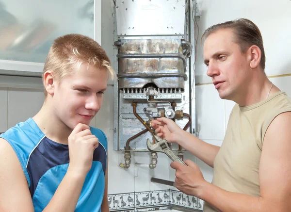 Far och son-tonåringen tillsammans i reparation en gas vattenvärmaren. — Stockfoto