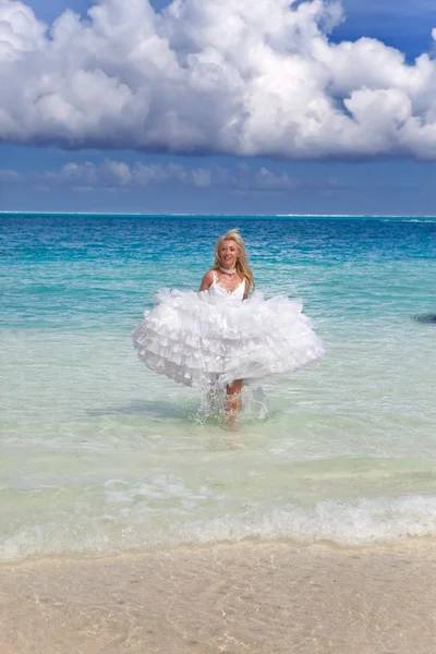 A bela mulher jovem em um vestido da noiva corre em ondas do mar — Fotografia de Stock