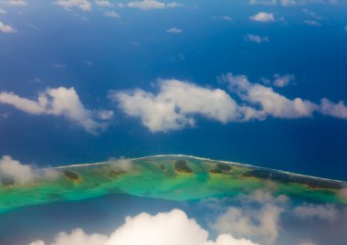 atoll ocean yüzüğe Bulutların arasından görünür. Havadan görünümü.