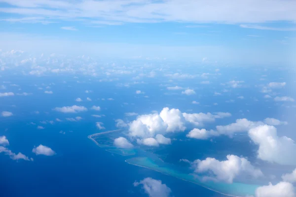 Pierścień atolu w Oceanie jest widoczne przez chmury. widok z lotu ptaka. — Zdjęcie stockowe