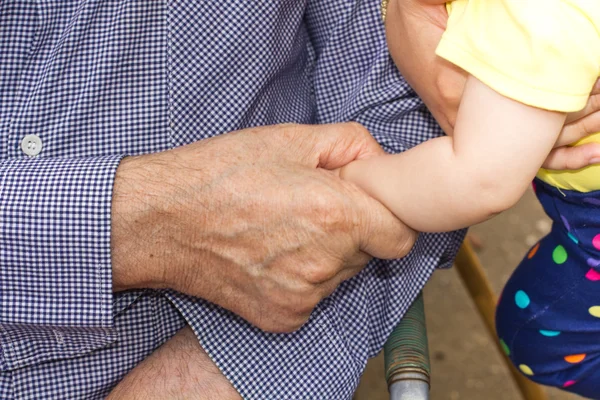 Senior man holding baby hands — Stock Photo, Image