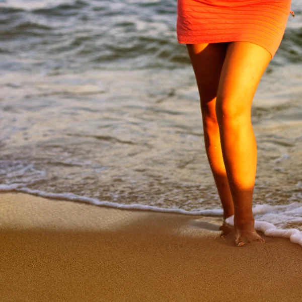 Las piernas de la mujer en la playa de arena — Foto de Stock