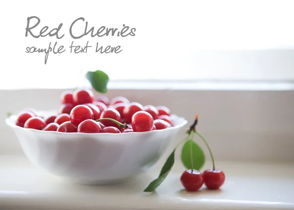 Red cherries in white bowl — Stock Photo, Image