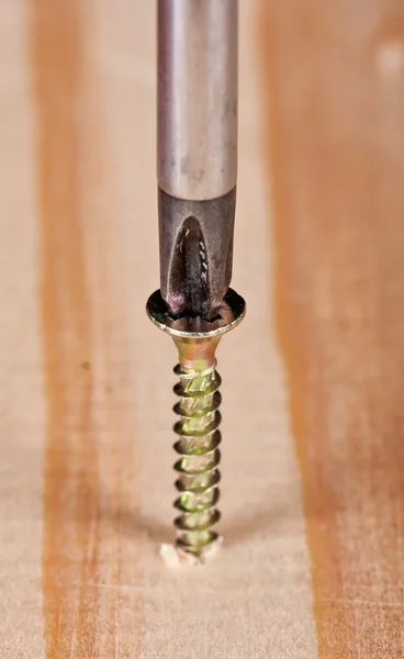 Parafuso de perfuração de chave de fenda na superfície de madeira — Fotografia de Stock