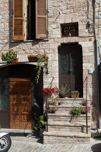 Flowers in pots on the stone steps medieval house in Tuscany