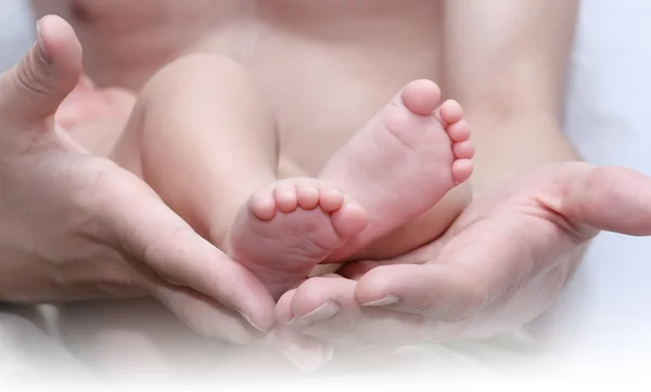 Man's hand and children's foot — Stock Photo, Image