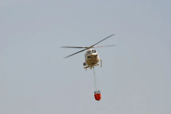 Helikopter strażak, niosąc wiadro wody — Zdjęcie stockowe