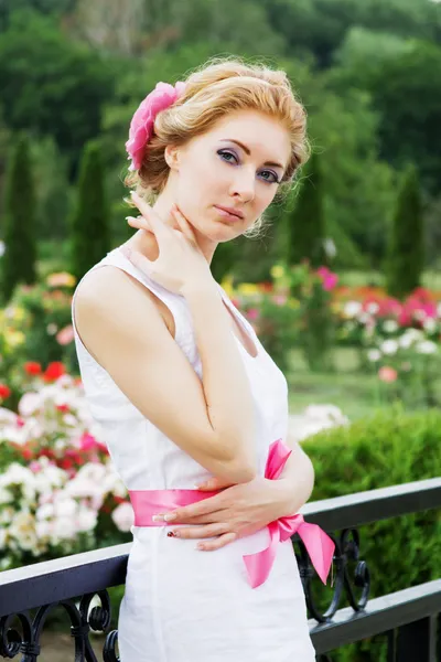Romantisk kvinna bland rosenträdgård — Stockfoto