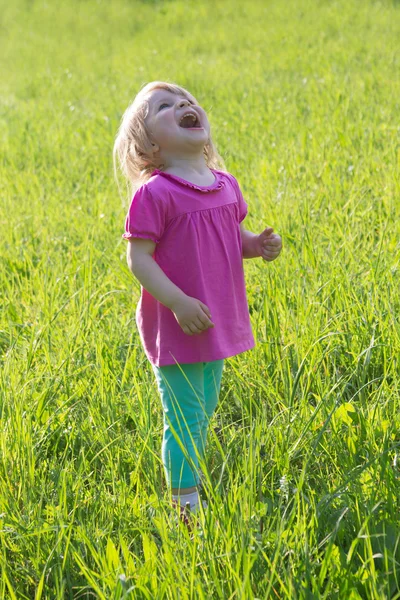 Joyful baby girl looking up in medow — Stock Photo, Image