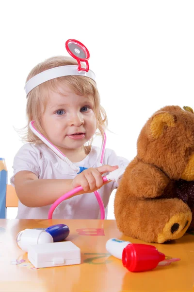 小さな女の子が医者として聴診器で遊んで ストックフォト