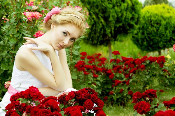 Kobieta w białej sukni wśród ogród różany — Zdjęcie stockowe