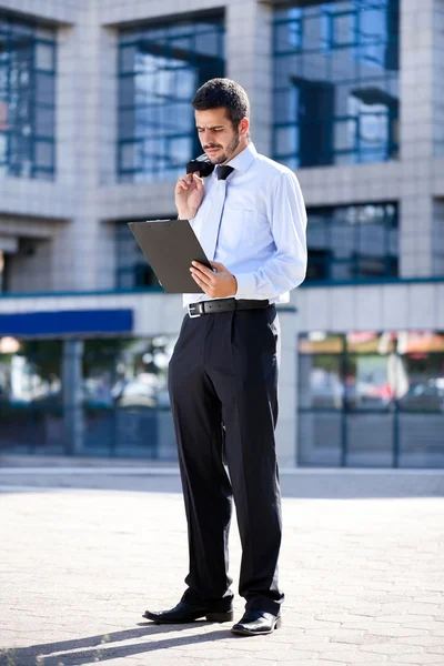 Affärsman läser dokument utanför en byggnad — Stockfoto
