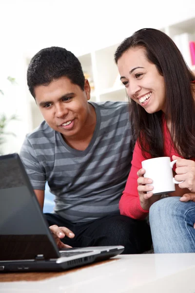 Happy couple sitting together using laptop at home — Stock Photo, Image