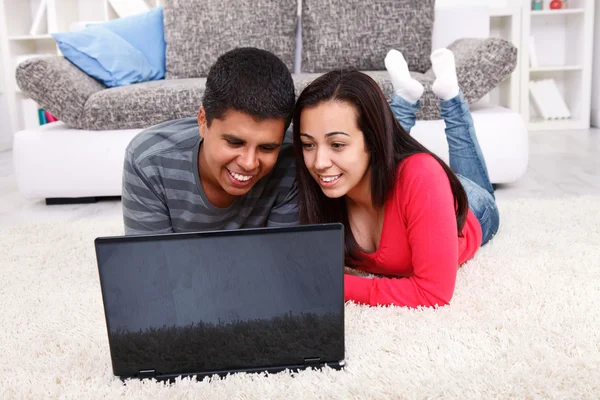 Feliz jovem casal usando um computador portátil — Fotografia de Stock