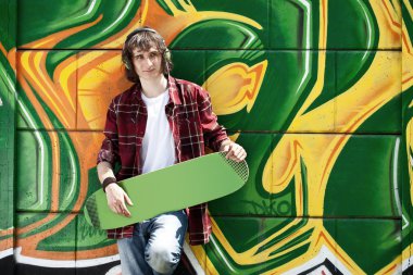 Young man listening music near a graffiti wall clipart