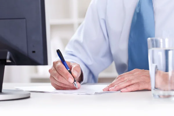 Affärsman som sitter vid office skrivbord underteckna ett kontrakt — Stockfoto