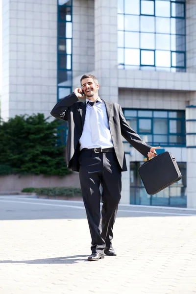 Empresário andando e chamando no telefone celular — Fotografia de Stock