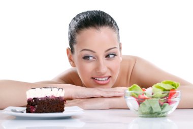 Woman choosing between healthy food and tasty cakes