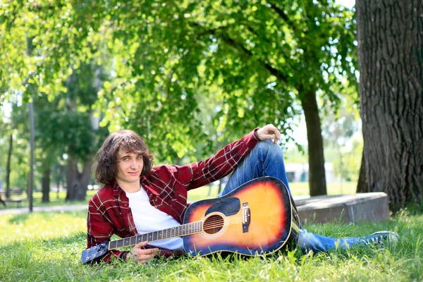 Man in park with acoustic guitar — Stock Photo, Image