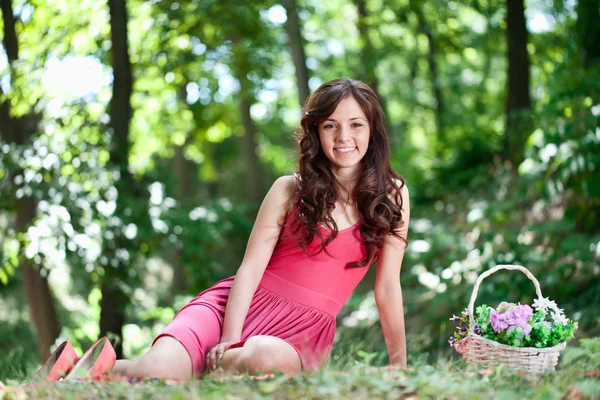 Uśmiechnięta młoda dziewczyna siedzi na trawie — Zdjęcie stockowe