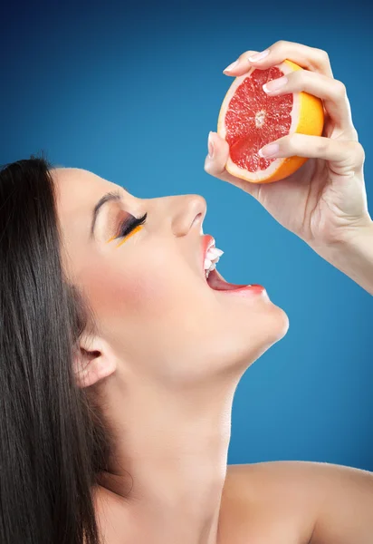 Kobieta ściskając pomarańczowe w ustach — Zdjęcie stockowe