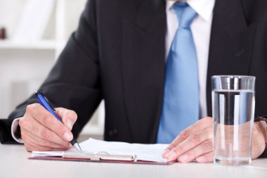 Businessman writes with pen on paperwork clipart