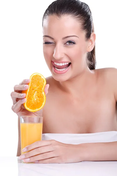 Mulher sorridente segurando laranja e espreme em um copo — Fotografia de Stock
