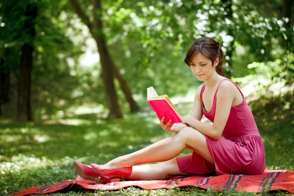 Красивая девушка читает книгу под открытым небом — стоковое фото