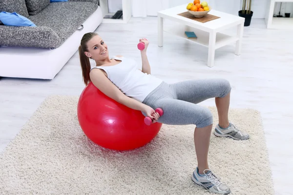 Девушка лежит на фитнес-мяч и упражнения с гантелями — стоковое фото