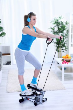 Woman exercising at home on stepper trainer clipart