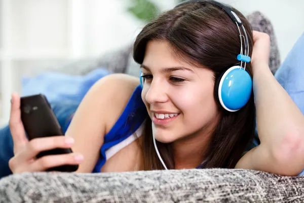 Teenager holds smartphone and listens to music — Stock Photo, Image