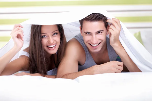 Young couple playing under the sheets — Stock Photo, Image