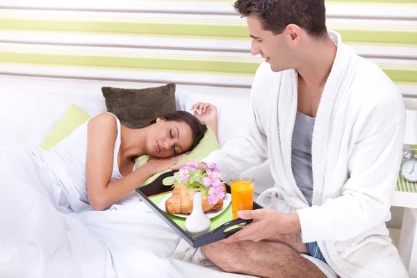 침대에서 그의 여자 친구에 대 한 아침 식사를 제공 하는 젊은 남자 — 스톡 사진