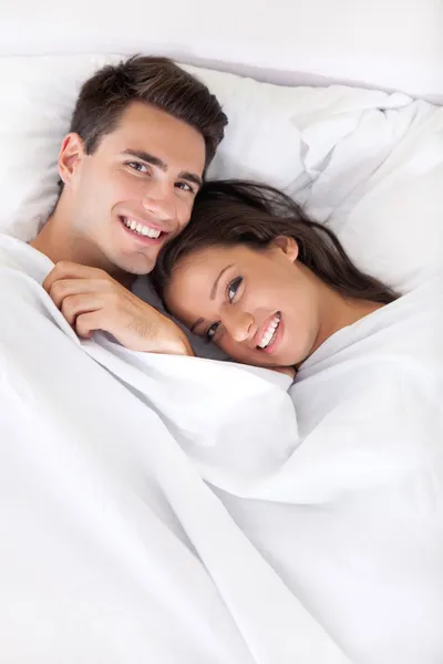 Unga lyckliga paret i sängen — Stockfoto