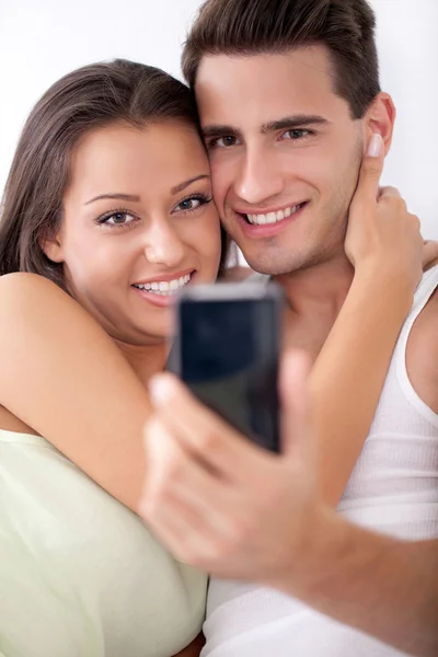 Улыбающаяся пара фотографирует с мобильного телефона — стоковое фото