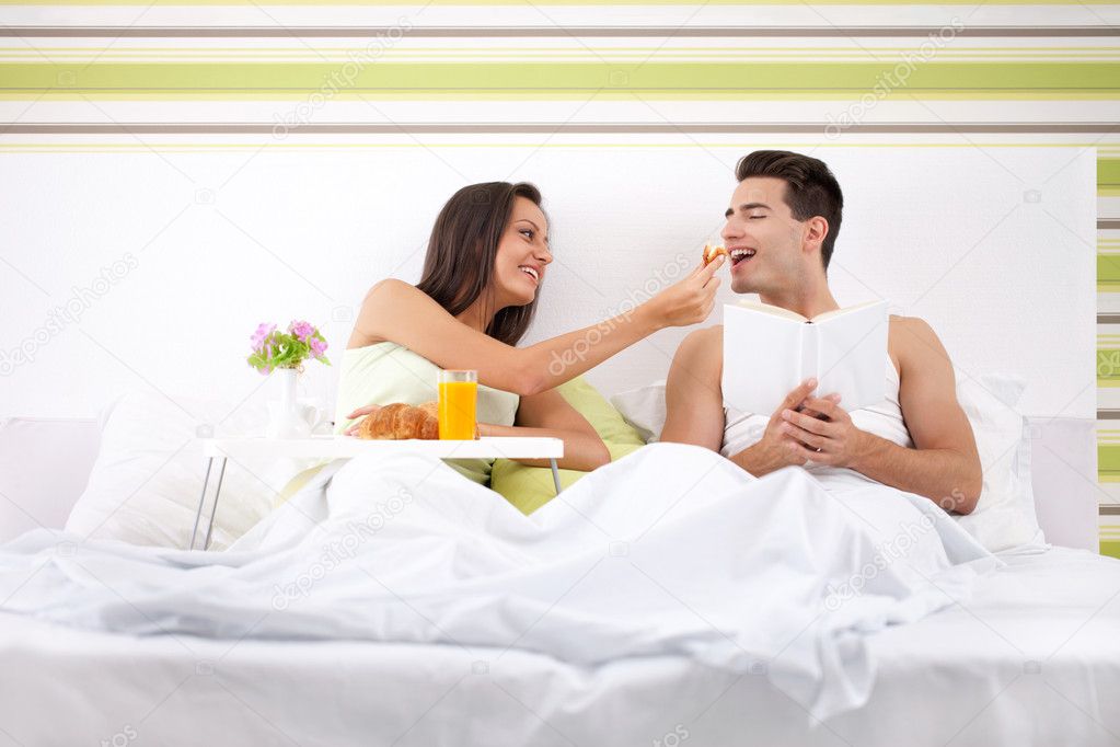 Young and beautiful couple having breakfast in bed