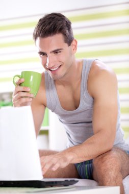 Young men in pajama using laptop clipart