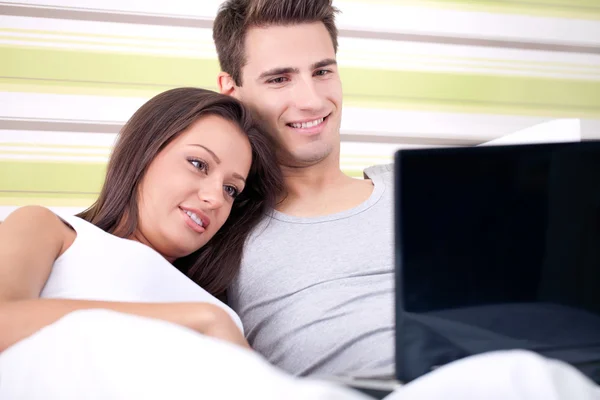 Couple using laptop in bed — Stock Photo, Image