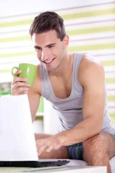 Fiatal férfi pizsama használ laptop — Stock Fotó