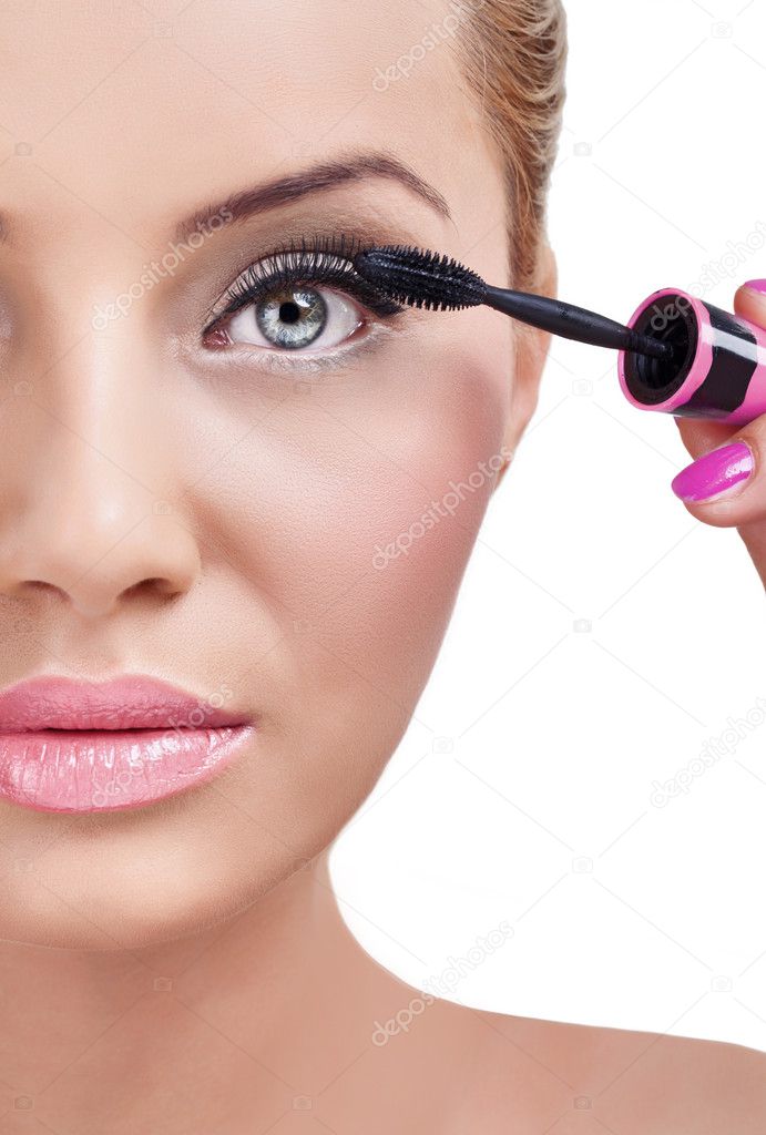 Woman putting mascara makeup.
