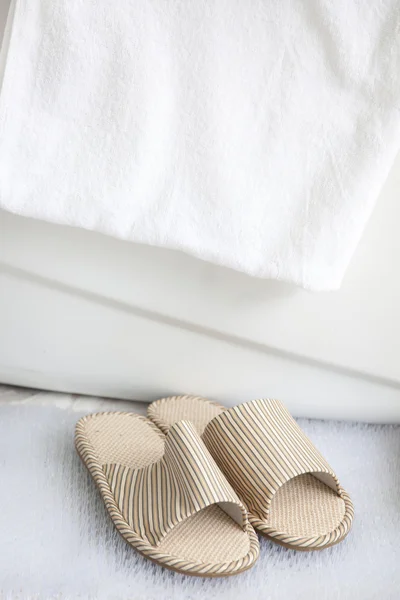 Chinelos e toalha de banho junto à banheira — Fotografia de Stock