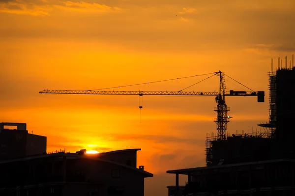 Промышленные строительные краны и строительные силуэты с солнцем — стоковое фото
