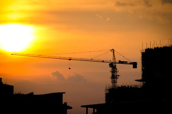 Endüstriyel İnşaat vinçleri ve bina siluetleri ile güneş — Stok fotoğraf