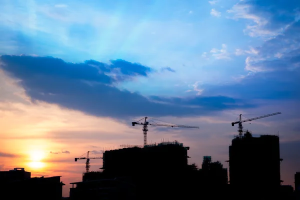 Industrial construction cranes and building silhouettes at sunse — Stock Photo, Image