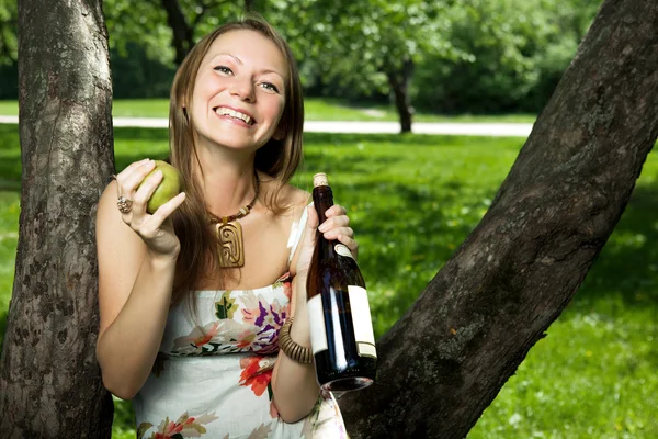 Portrait of laughing girl with wine and pear in the apple orchar Stok Resim