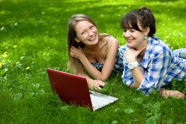 iki çekici kız parkta bir dizüstü bilgisayar ile
