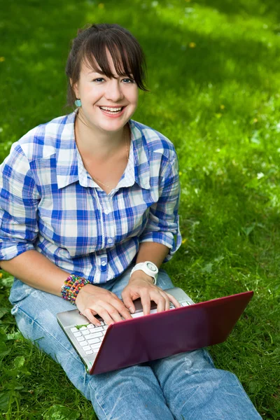 Chica atractiva con un ordenador portátil en el parque —  Fotos de Stock